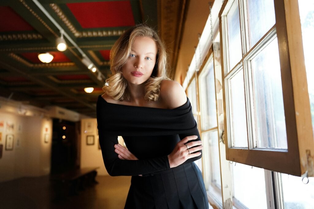 a woman standing in front of a window with her arms crossed